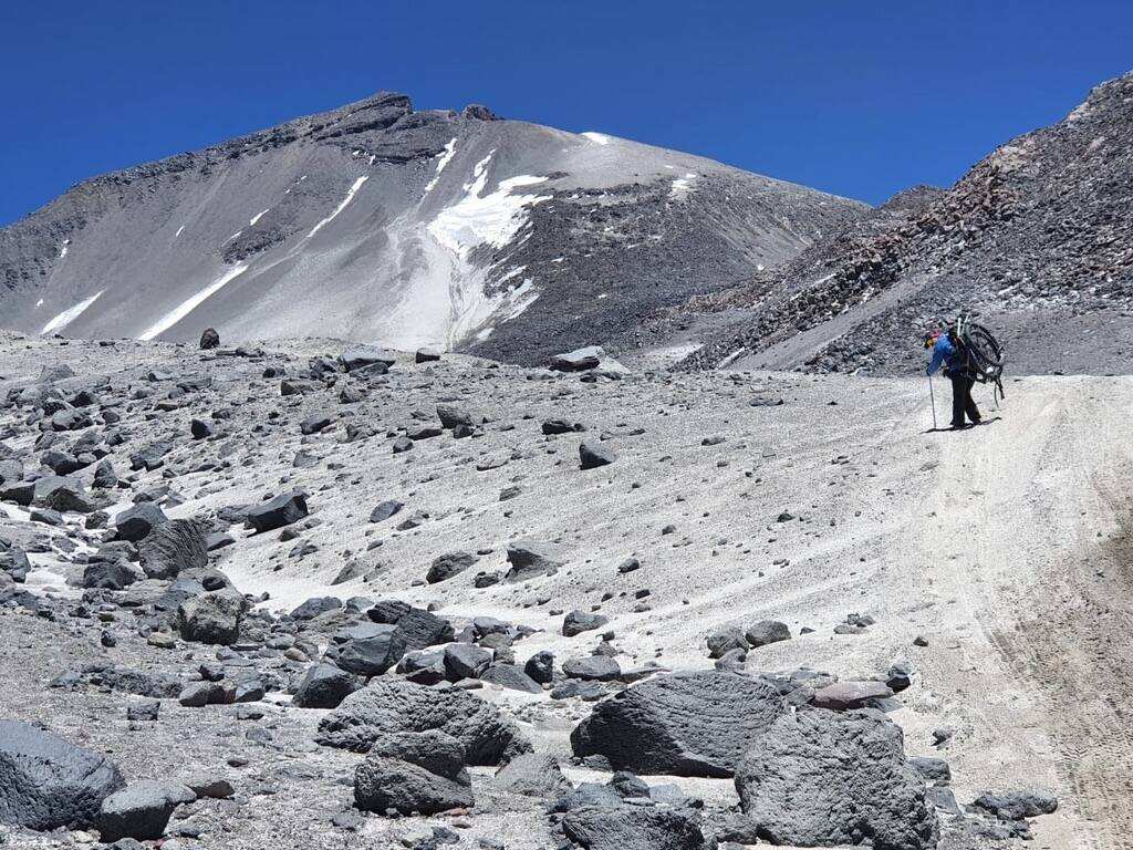 Climber on the long approach across snow-streaked Andean slopes