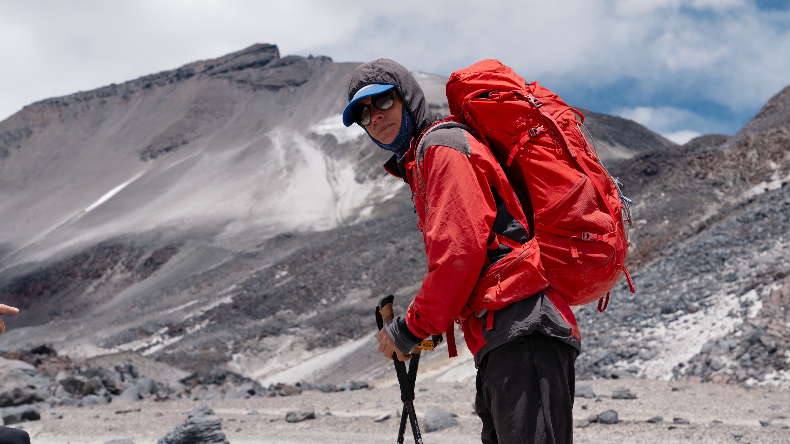 Jean-Marie Dupré Navarrete, Mountain Guide, carrying a red expedition pack on rocky mountain terrain