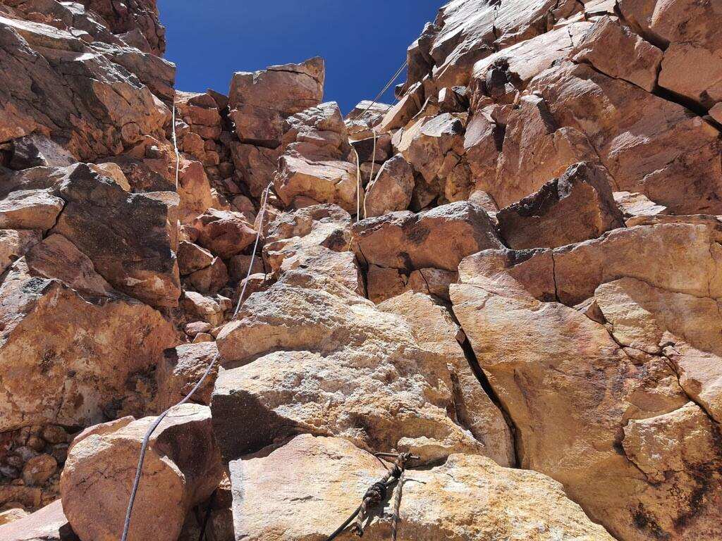 Looking up a steep rock pitch with a fixed line in the Atacama