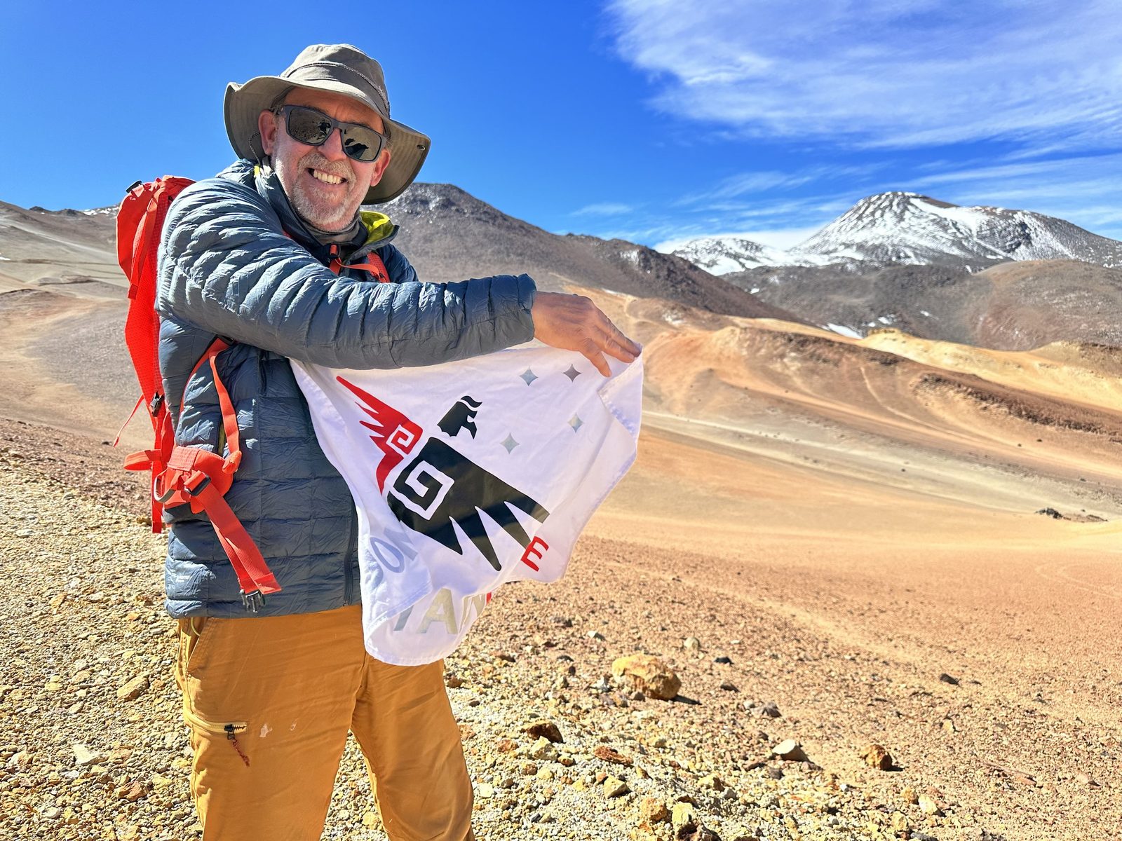 Steve Birchfield with the Pan American Adventures flag on a volcanic ridge in the Atacama